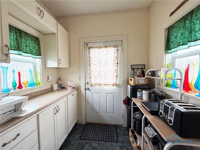 kitchen featuring dark tile patterned floors and white cabinetry