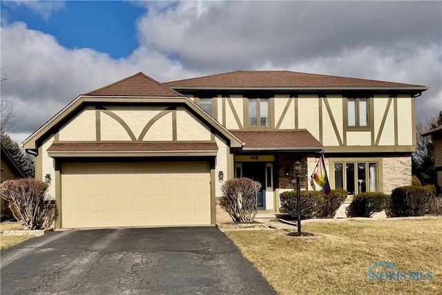 tudor-style house with a garage and a front yard