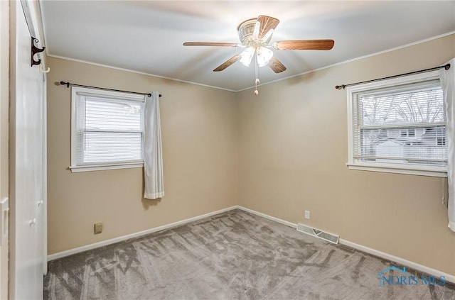 carpeted spare room with crown molding, ceiling fan, and a wealth of natural light