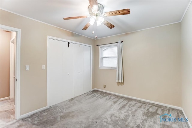 unfurnished bedroom featuring crown molding, light carpet, ceiling fan, and a closet