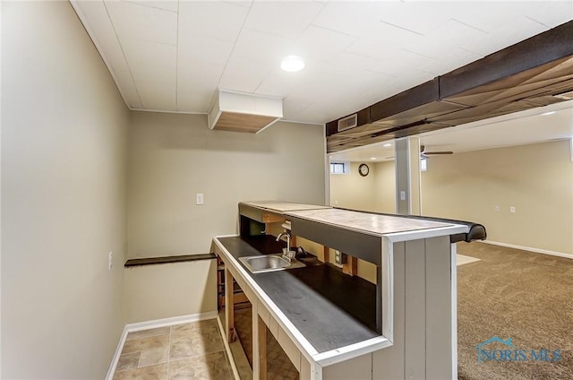 kitchen featuring sink, light colored carpet, kitchen peninsula, and stainless steel counters