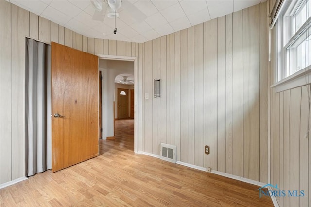 spare room featuring wood walls, ceiling fan, and light hardwood / wood-style flooring