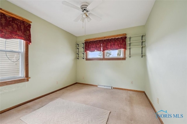 spare room with ceiling fan, light colored carpet, and a baseboard heating unit