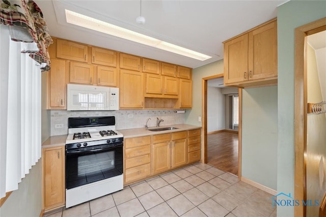 kitchen with light tile patterned flooring, tasteful backsplash, sink, gas stove, and light brown cabinets