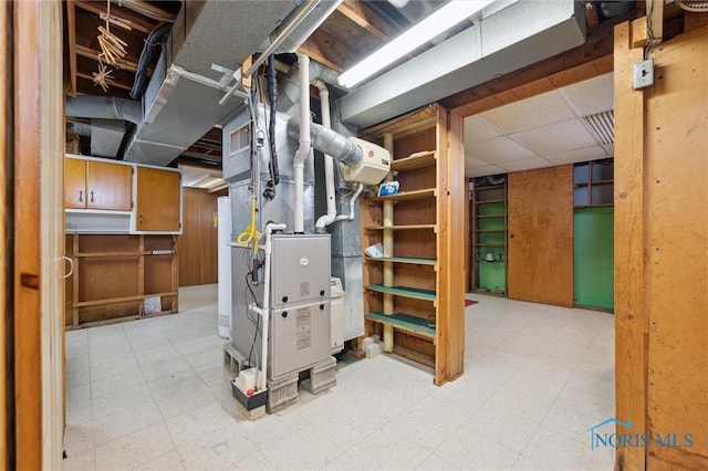 basement with a paneled ceiling and heating unit