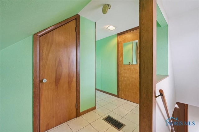 hallway with lofted ceiling and light tile patterned floors