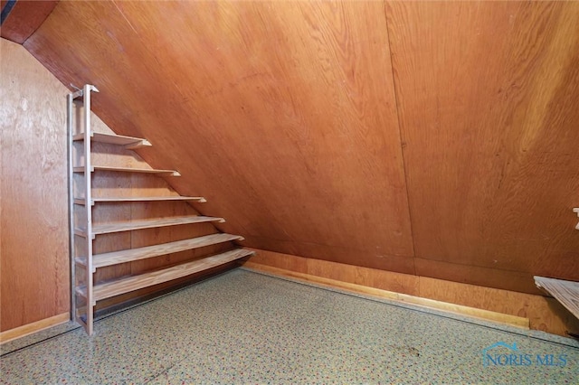 stairway featuring vaulted ceiling, wooden ceiling, and wooden walls