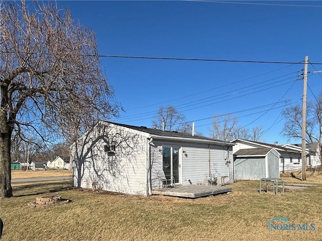 rear view of property featuring a storage shed, a wooden deck, an outbuilding, and a yard