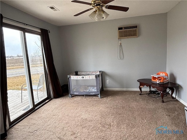 interior space featuring ceiling fan, visible vents, baseboards, an AC wall unit, and carpet