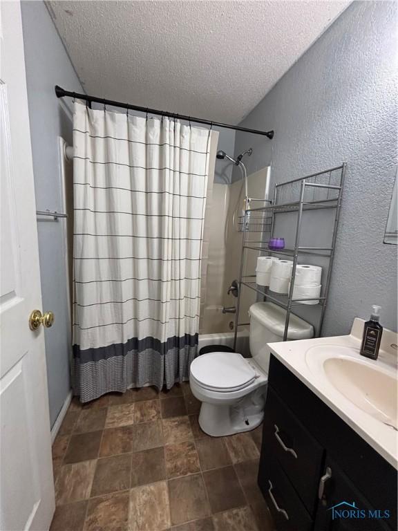 bathroom featuring a textured ceiling, a textured wall, toilet, shower / tub combo, and vanity