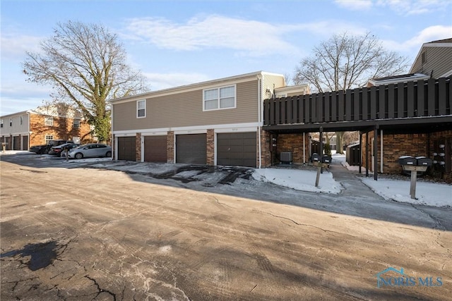 view of snowy exterior with a garage and central air condition unit