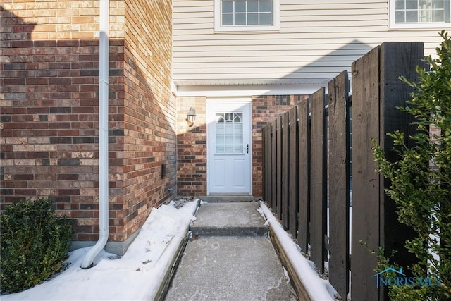 property entrance featuring brick siding and fence