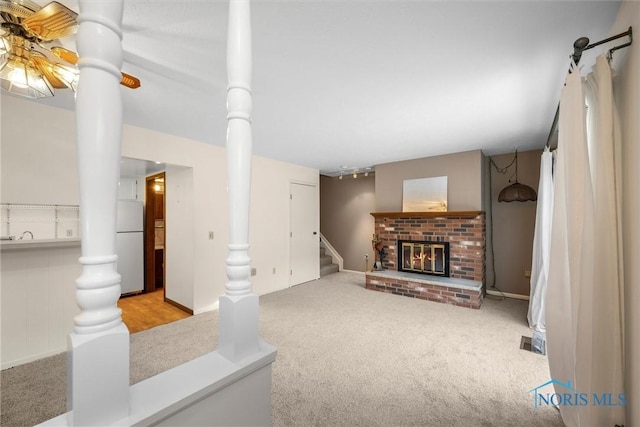 unfurnished living room with light carpet, a fireplace, and stairway