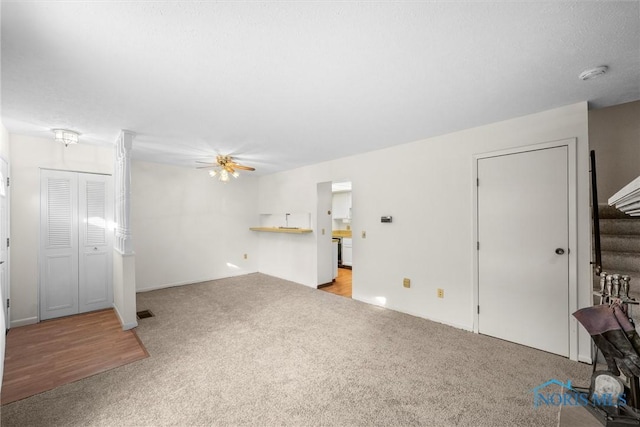 unfurnished living room featuring stairway, a ceiling fan, and light colored carpet