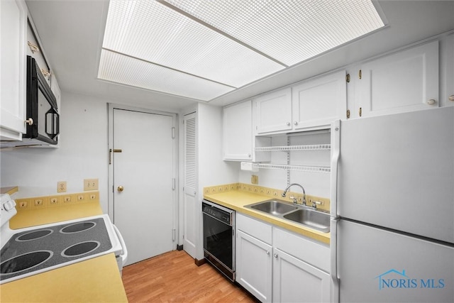 kitchen featuring light wood-style flooring, a sink, white cabinets, light countertops, and black appliances