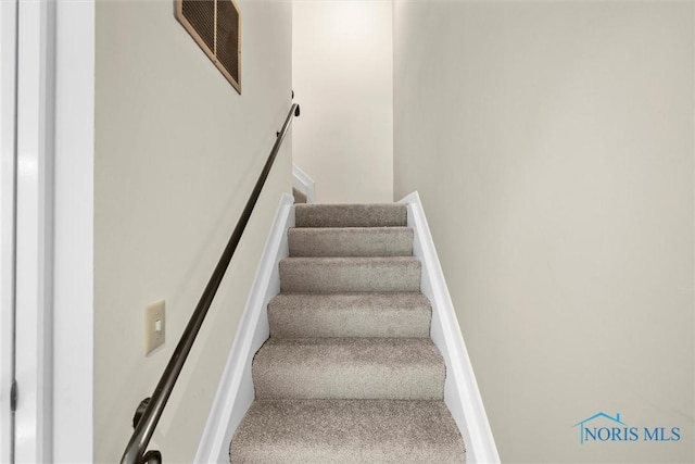 stairway featuring visible vents and carpet flooring