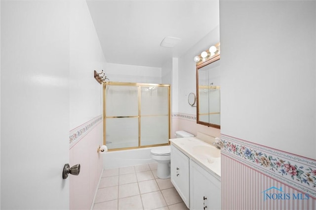 full bathroom featuring a wainscoted wall, toilet, enclosed tub / shower combo, vanity, and tile patterned flooring