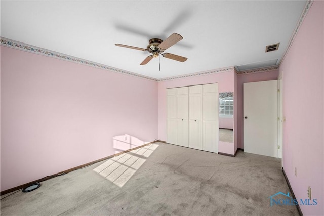 unfurnished bedroom with a closet, visible vents, light carpet, ceiling fan, and baseboards