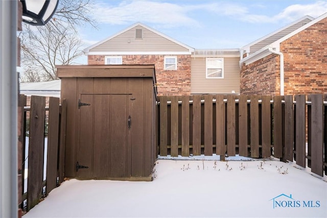 yard covered in snow with fence, an outdoor structure, and a storage unit