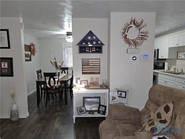 living room featuring sink, dark wood-type flooring, and ceiling fan