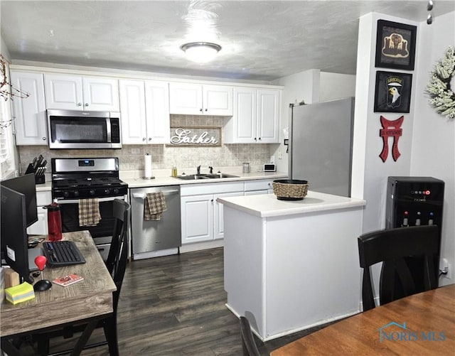 kitchen with sink, appliances with stainless steel finishes, tasteful backsplash, white cabinets, and dark hardwood / wood-style flooring