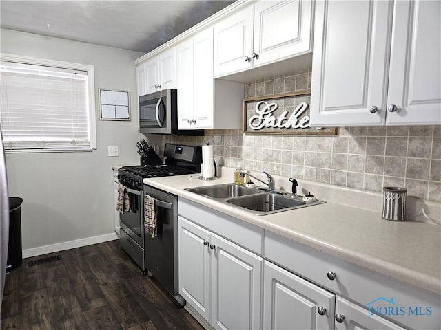 kitchen featuring sink, appliances with stainless steel finishes, dark hardwood / wood-style floors, white cabinets, and backsplash