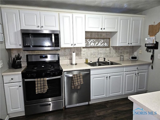 kitchen featuring appliances with stainless steel finishes, dark hardwood / wood-style floors, sink, white cabinets, and decorative backsplash