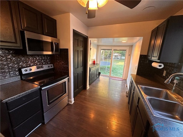 kitchen with sink, appliances with stainless steel finishes, dark brown cabinets, dark hardwood / wood-style floors, and tasteful backsplash