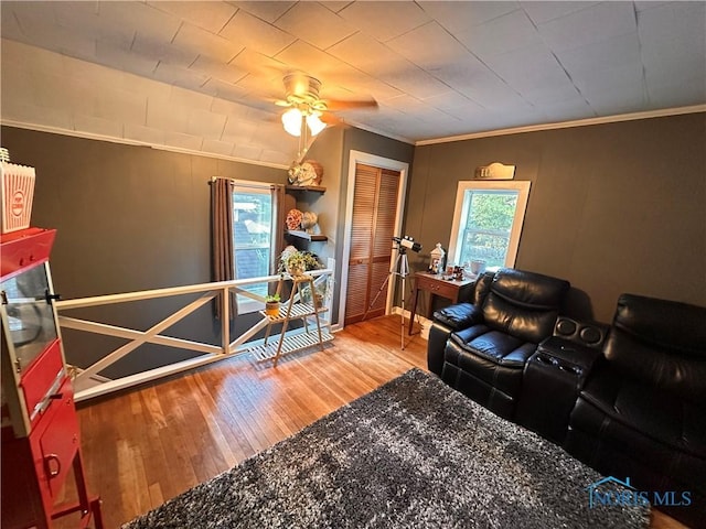 living room with wood-type flooring, ornamental molding, and ceiling fan