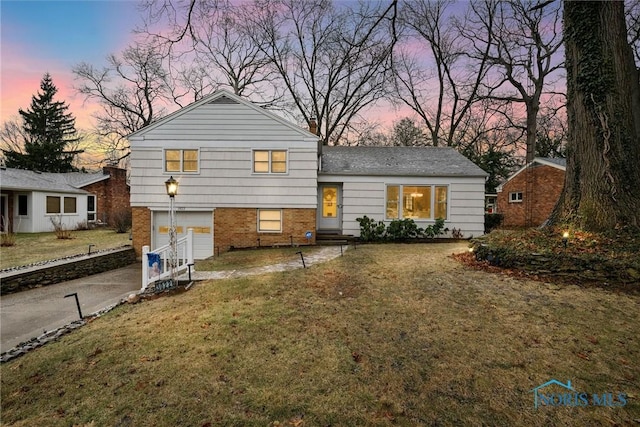 tri-level home with a garage and a lawn