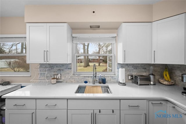 kitchen with tasteful backsplash, sink, plenty of natural light, and white cabinets