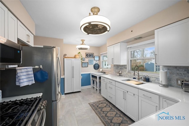 kitchen featuring appliances with stainless steel finishes, sink, decorative backsplash, and white cabinets