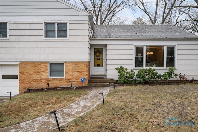 entrance to property with a garage and a lawn