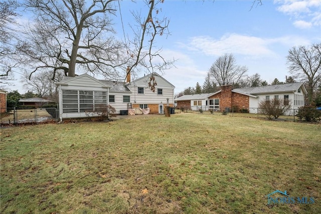 back of house featuring a lawn and a sunroom