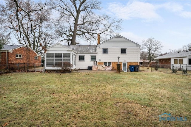 rear view of property featuring a sunroom and a lawn