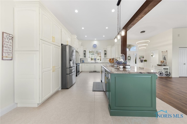 kitchen featuring pendant lighting, sink, stainless steel fridge, white cabinetry, and a kitchen island