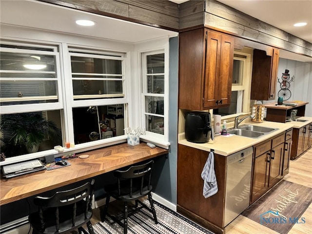 kitchen with sink, built in desk, dishwasher, and light wood-type flooring