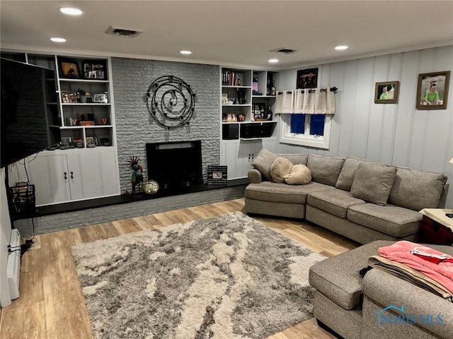 living room featuring hardwood / wood-style flooring, a large fireplace, and built in shelves