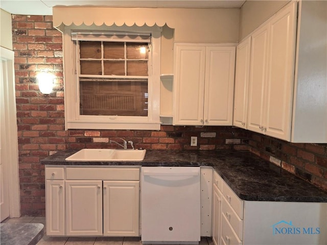 kitchen featuring white cabinetry, dishwasher, brick wall, and sink