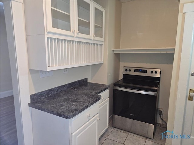 kitchen featuring electric stove, white cabinetry, and light tile patterned flooring