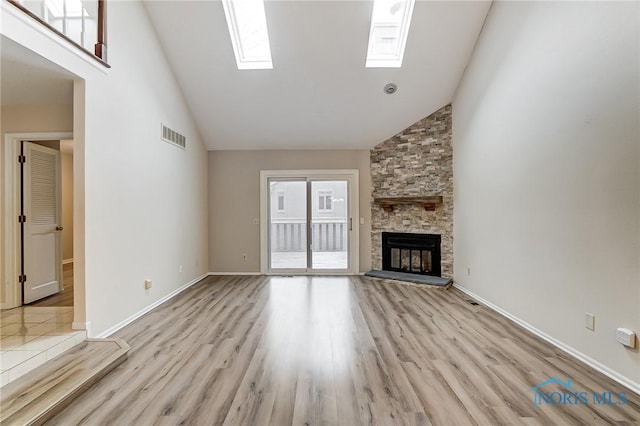 unfurnished living room with a fireplace, high vaulted ceiling, and light wood-type flooring