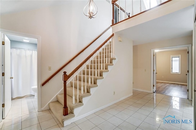 stairs with a towering ceiling and tile patterned floors