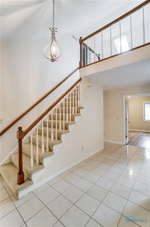 stairway with a high ceiling and tile patterned floors