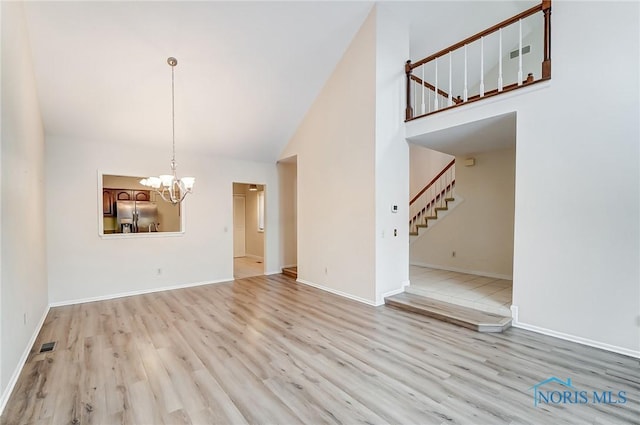 32 Abbey Rd, Perrysburg, OH 43551 - unfurnished living room featuring baseboards, a notable chandelier, stairway, wood finished floors, and high vaulted ceiling