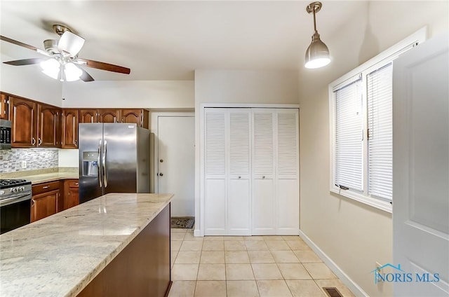 kitchen featuring light tile patterned floors, ceiling fan, appliances with stainless steel finishes, backsplash, and decorative light fixtures