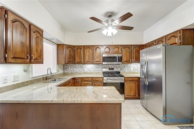 kitchen featuring sink, light tile patterned floors, appliances with stainless steel finishes, decorative backsplash, and kitchen peninsula