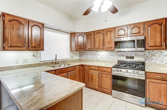 kitchen with light tile patterned flooring, sink, appliances with stainless steel finishes, light stone countertops, and backsplash