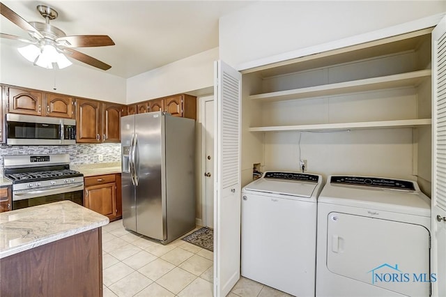 kitchen featuring light tile patterned floors, appliances with stainless steel finishes, ceiling fan, washer and clothes dryer, and decorative backsplash