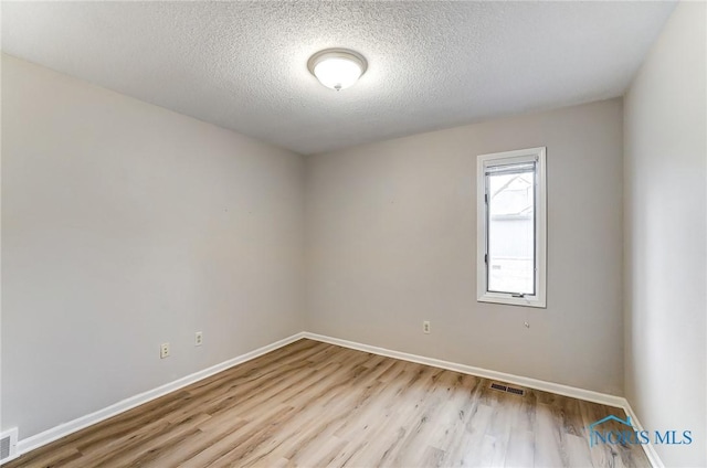 unfurnished room with a textured ceiling and light wood-type flooring