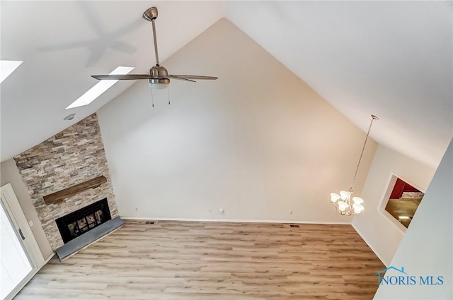 unfurnished living room featuring ceiling fan with notable chandelier, a fireplace, high vaulted ceiling, and light hardwood / wood-style flooring